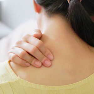 rear view close up asian woman has shoulder and neck pain in living room at home